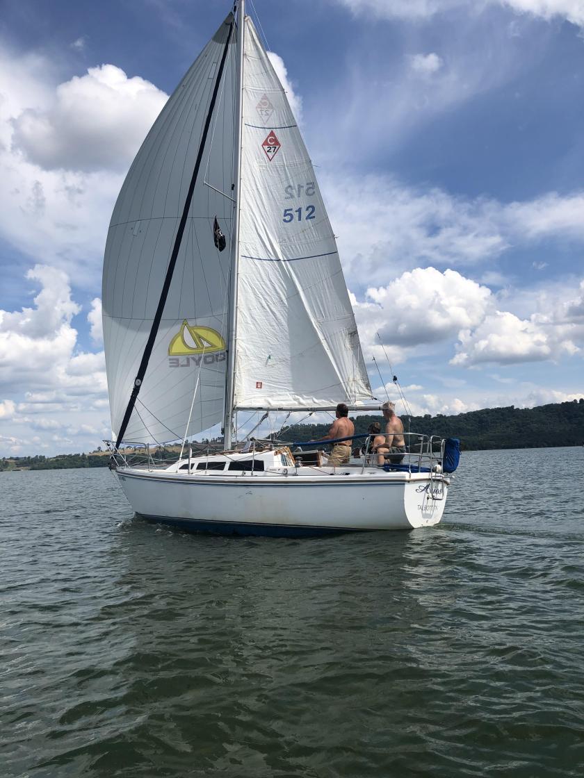 Sailboat sails downwind on tranquil lake water