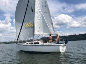 Sailboat sails downwind on tranquil lake water