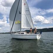 Sailboat sails downwind on tranquil lake water